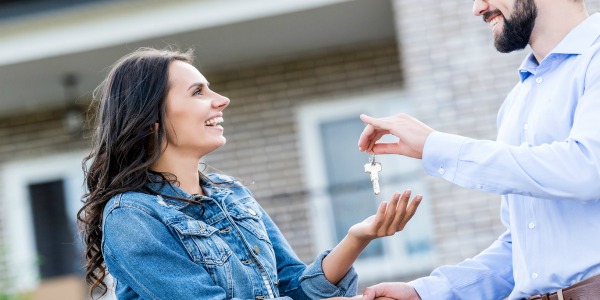 young happy woman buying new house and taking keys from realtor